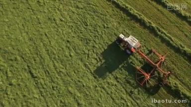 阳光明媚的山里，拖拉机的天线在田野上收集干草，形成一条绿色的线